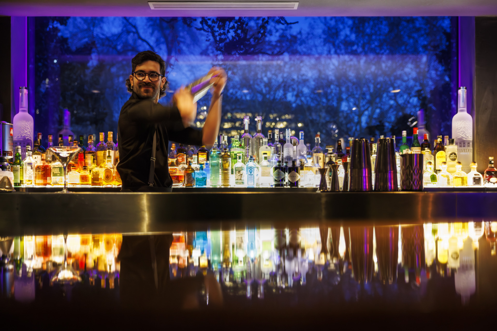 Person making cocktail behind a bar